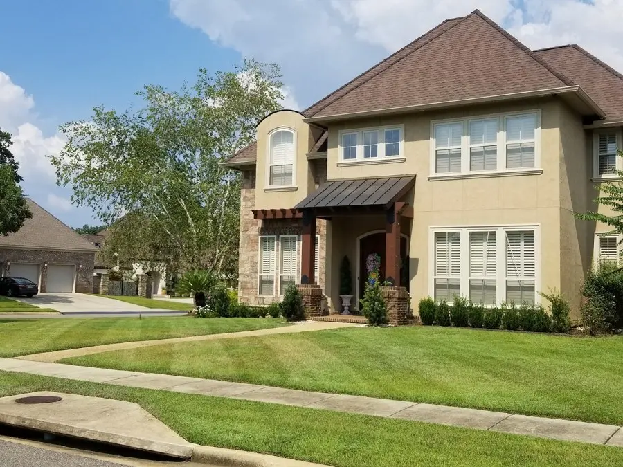 Two-story home with a trimmed lawn and beds