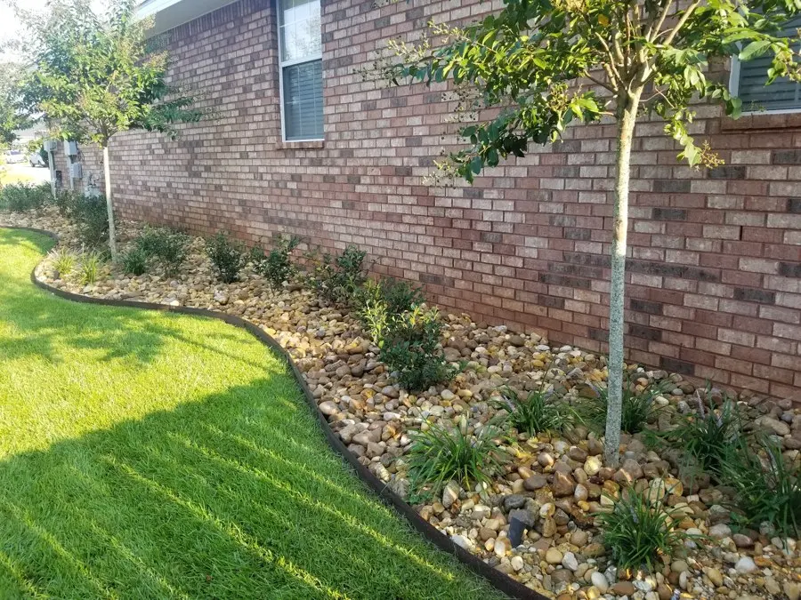 Rock border and young tree along a brick home